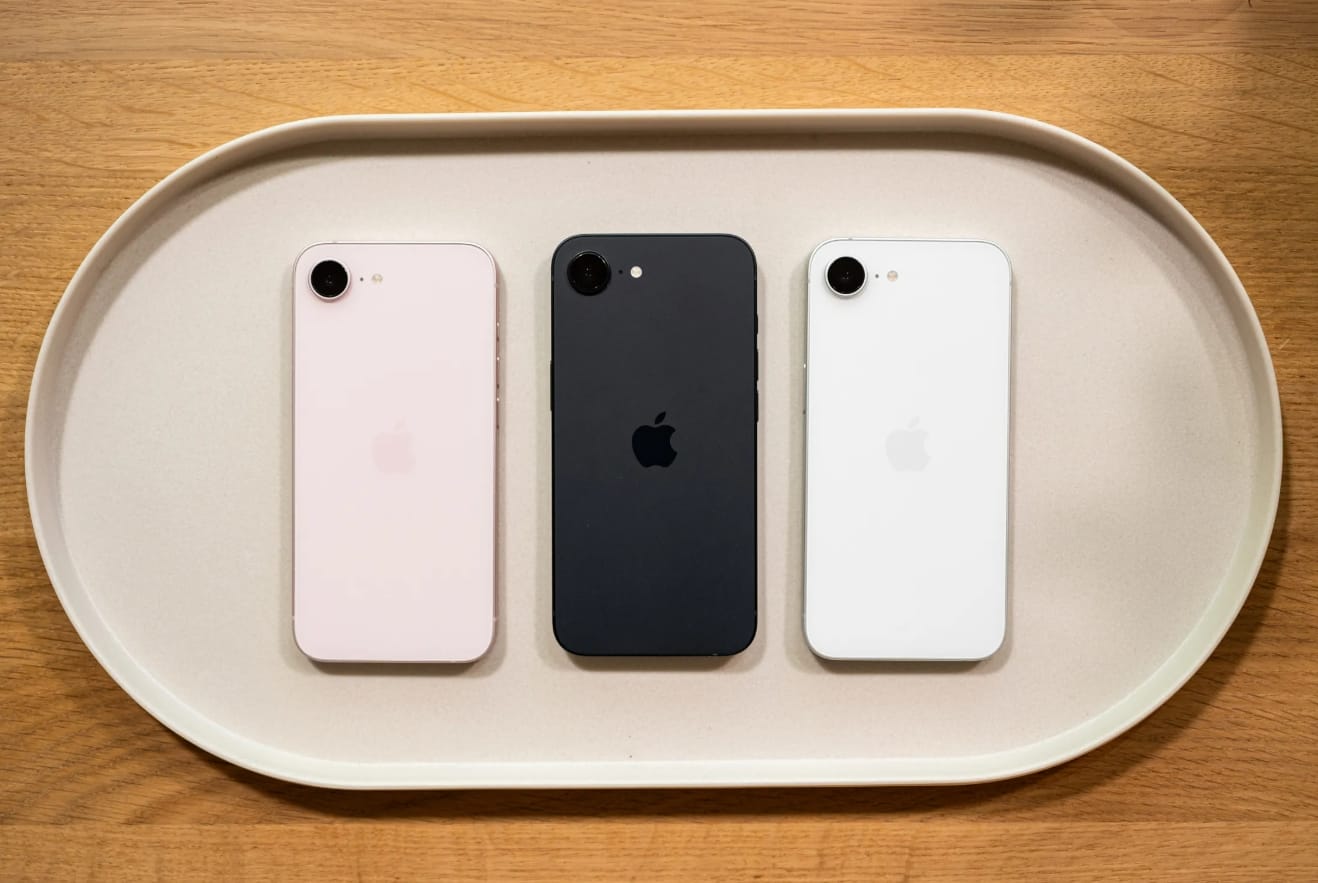 Apple iPhone 17e單鏡頭手機 多色機身展示，粉色、黑色與白色背面排列於托盤上，呈現單鏡頭與閃光燈配置及 Apple 標誌