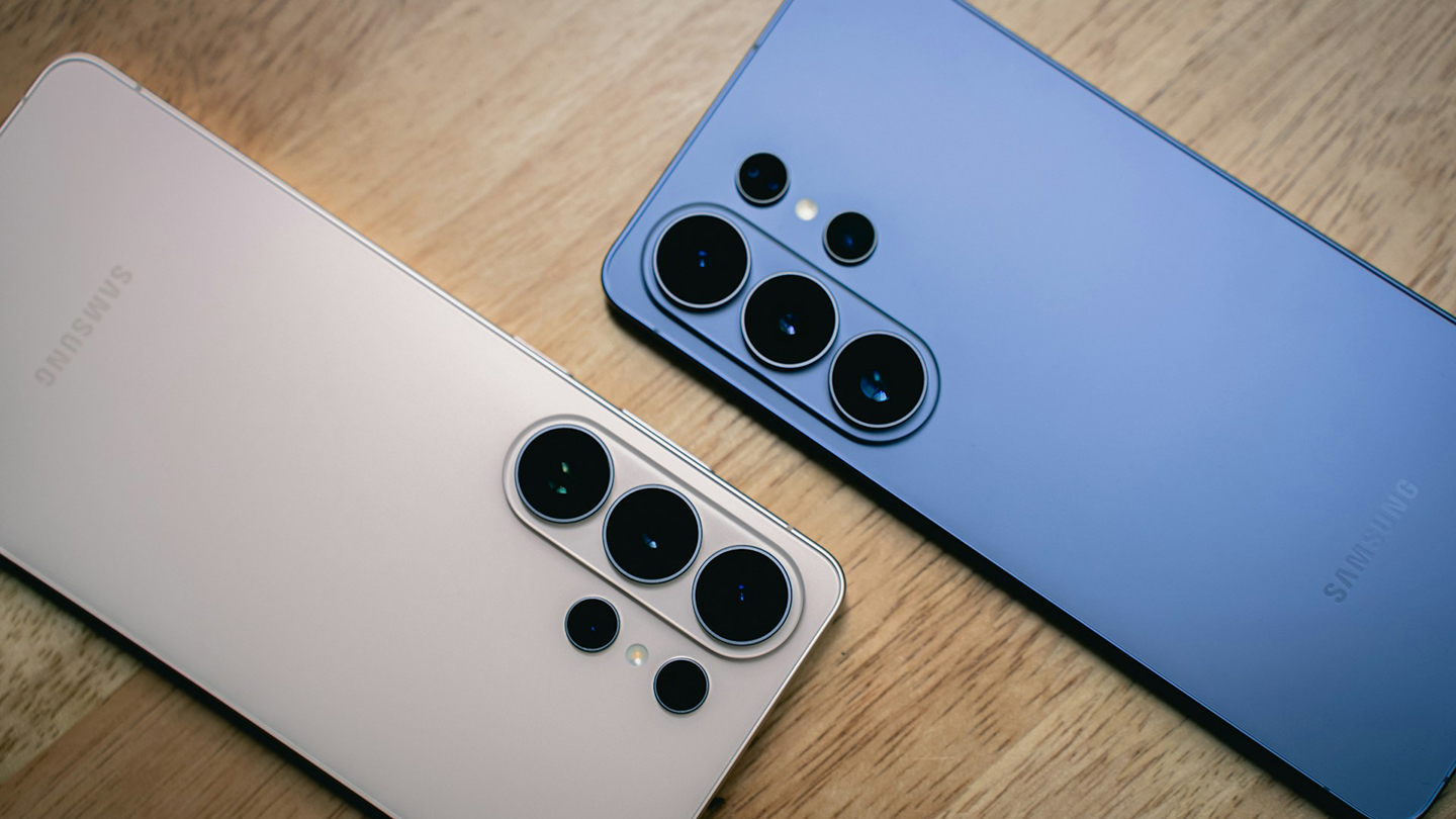 Samsung Galaxy S26 Ultra 粉金色與藍色機身背面並排放在木桌上，清楚呈現多鏡頭相機模組與霧面背蓋設計。